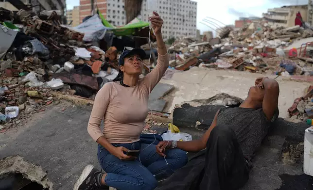Eduardo Lopez receives medical assistance by a nurse after he has been 16 days removing debris on a collapse building by the earthquakes searching for their love ones in La Guaira, Venezuela, Sunday, July 12, 2026. (AP Photo/Ariana Cubillos)