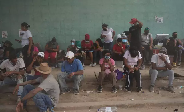 Relatives sit on a sidewalk as they wait for workers remove rubble from collapse buildings by the earthquakes, looking to find their loved ones in La Guaira, Venezuela, Thursday, July 23, 2026. (AP Photo/Ariana Cubillos)