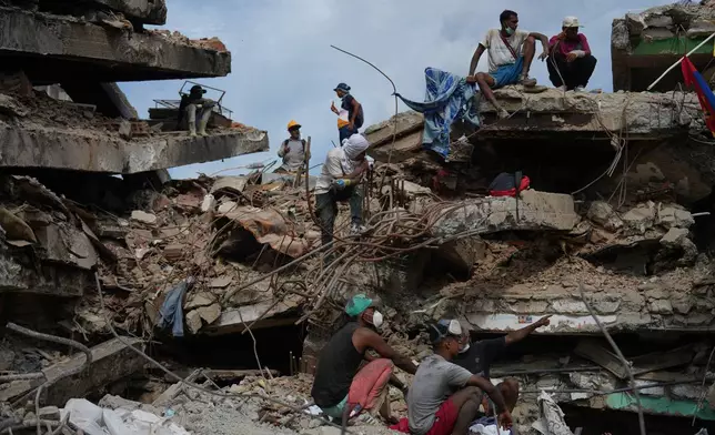 People stand on a collapsed building by the earthquakes in La Guaira, Venezuela, Thursday, July 23, 2026. (AP Photo/Ariana Cubillos)
