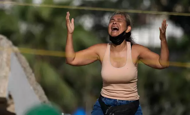 FILE - Carolina Munoz prays as she searches for the body of her son, Carlos Munoz, in the debris of a building collapsed by an earthquake in La Guaira, Venezuela, July 15, 2026. (AP Photo/Ariana Cubillos, File)