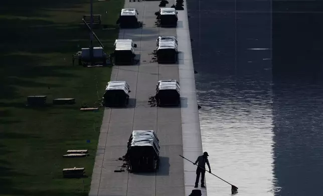 A worker clears debris from the Lincoln Memorial Reflecting Pool, Wednesday, July 1, 2026, in Washington. (AP Photo/Tom Brenner)