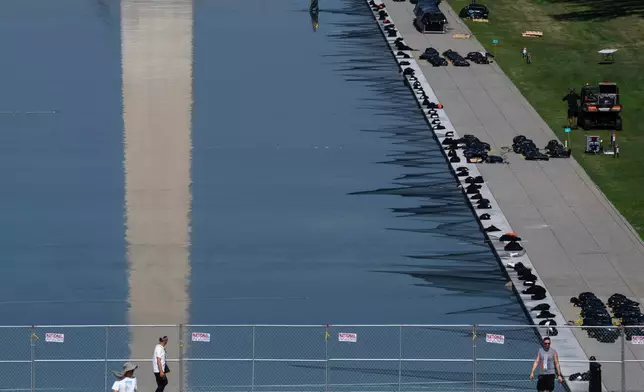 Workers install fireworks along the edge of the Lincoln Memorial Reflecting Pool ahead of the America 250 July 4th celebration on the National Mall, Thursday, July 2, 2026, in Washington. (AP Photo/Nathan Howard)