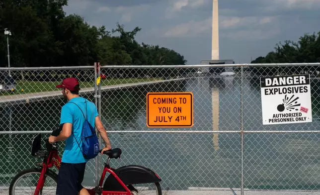 A man on a bike passes security fencing along the edge of the Lincoln Memorial Reflecting Pool ahead of America 250 July 4th celebration on the National Mall, Thursday, July 2, 2026, in Washington. (AP Photo/Nathan Howard)