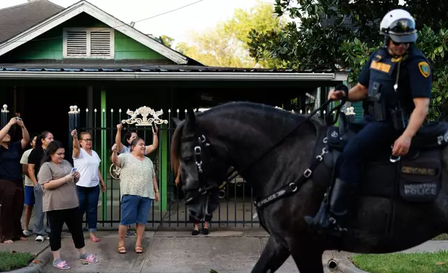 Neighbors cheer as marchers walk past during a vigil for Lorenzo Salgado Araujo, a Mexican national fatally shot by a federal immigration agent a day prior, Wednesday, July 8, 2026, in Houston. (AP Photo/Mark Felix)