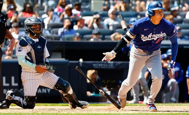 Los Angeles Dodgers' Shohei Ohtani, right, tosses his bat after hitting an RBI single against the New York Yankees during the eighth inning of the first game of a baseball doubleheader, Sunday, July 19, 2026, in New York. (AP Photo/Noah K. Murray)