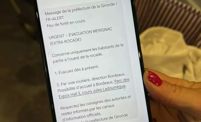 Evacuee Morgane Bonichot, 40, sheltering in an evacuation center in Bordeaux, France, on Tuesday, July 28, 2026, shows an evacuation message she received on her mobile phone on Saturday, July 25, ordering her to flee wildfires in southwest France's Gironde region. (AP Photo/Eva van Dam) ADDITION: message received on Saturday, July 25