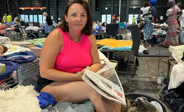 Morgane Bonichot, 40, takes a break from reading a newspaper in an evacuation center in Bordeaux, on Tuesday, July 28, 2026, where she, her daughter, their rabbit and dog are sheltering from wildfires in southwest France. (AP Photo/Eva van Dam)