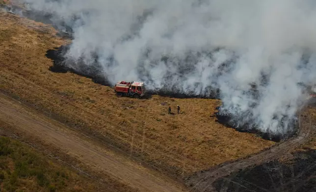 Firefighters work to suppress a fire near Ares, during wildfires in the area of southwestern France, Tuesday, July 28, 2026. (AP Photo/Baz Ratner, Pool)