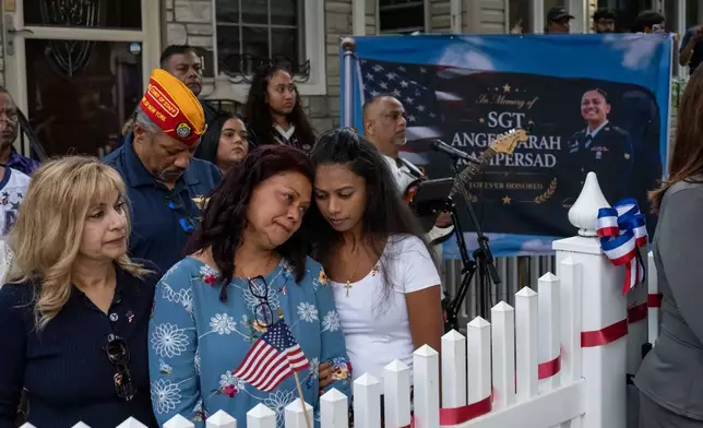 Family of Sgt. Angel Sarah Rampersad, aunt Judy Rackal, left, mother Carol Acevedo, center, and sister Laura Tamby, right, attend a candlelight vigil outside her home in Ozone Park, Monday, July 27, 2026, in the Queens borough of New York. (AP Photo/Yuki Iwamura)