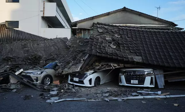 Vehicles are crushed under collapsed buildings in Yatsushiro, southwestern Japan, Wednesday, July 29, 2026, the day after an earthquake hit the area. (AP Photo/Hiro Komae)