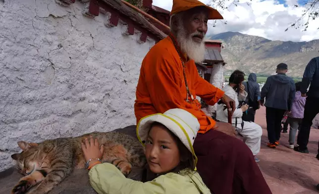 A child pets a cat during a visit to the Potala Palace in Lhasa in western China's Tibet Autonomous Region on Tuesday, July 21, 2026, as seen during a government organized visit for foreign journalists. (AP Photo/Ng Han Guan)