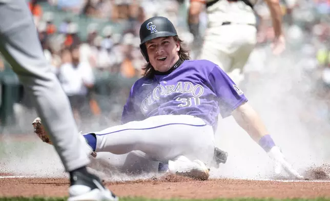 Colorado Rockies' Jake McCarthy slides into home plate to score during the first inning of a baseball game against the San Francisco Giants, Sunday, July 12, 2026, in San Francisco. (AP Photo/Thien-An Truong)