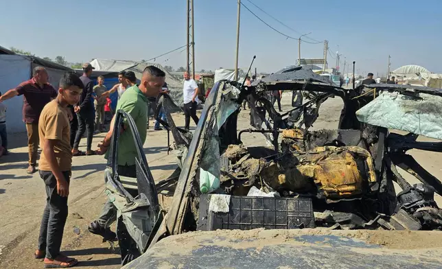 Palestinians look at a destroyed car following an Israeli military strike in Khan Younis, southern Gaza Strip, Monday, July 6, 2026, that, according to hospital officials, killed at least one person. (AP Photo/Mohammad Jahjouh)