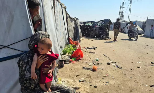 Palestinians look at a destroyed car following an Israeli military strike in Khan Younis, southern Gaza Strip, Monday, July 6, 2026, that, according to hospital officials, killed at least one person. (AP Photo/Mohammad Jahjouh)