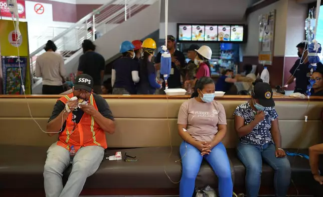 A man connected to an IV eats a hamburger at a McDonald's restaurant being used as a temporary health center and pet reunification center after the earthquakes that struck La Guaira, Venezuela, Thursday, July 2, 2026. (AP Photo/Matias Delacroix)