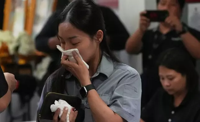 One of relatives of fire victims, front, leaves the Institute of Forensic Police hospital in Bangkok, Thailand, Monday, July 13, 2026, following a fire at a beer hall. (AP Photo/Sakchai Lalit)