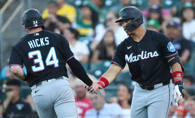 Miami Marlins' Heriberto Hernández, right, congratulates teammate Liam Hicks (34) after scoring on a sacrifice fly during the second inning of a baseball game against the Athletics, Friday, July 3, 2026, in West Sacramento, Calif. (AP Photo/Scott Marshall)