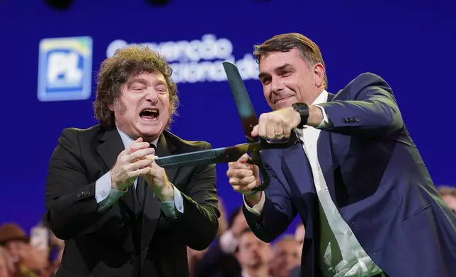 Brazilian Sen. Flavio Bolsonaro, right, handles an oversized pair of scissors, accompanied by Argentina's President Javier Milei during the Liberal Party convention where Bolsonaro was confirmed as the party's presidential candidate, in Sao Paulo, Saturday, July 25, 2026. (AP Photo/Ettore Chiereguini)