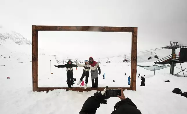 Tourists pose for a photo at the Farellones ski resort on the outskirts of Santiago, Chile, Saturday, July 25, 2026. (AP Photo/Esteban Felix)