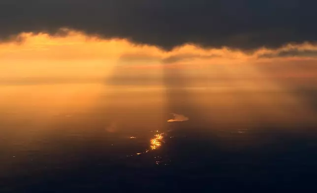 Light reflects off the water as the sun sets through wildfire smoke over Edmonton, Alberta, Friday, July 17, 2026. (AP Photo/Andy Bao)