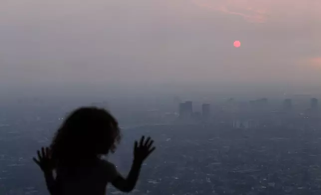 A child looks out from the observation deck of the CN Tower as smoke from wildfires in Northwestern Ontario blankets the city of Toronto, Thursday, July 16, 2026. (Cole Burston/The Canadian Press via AP)