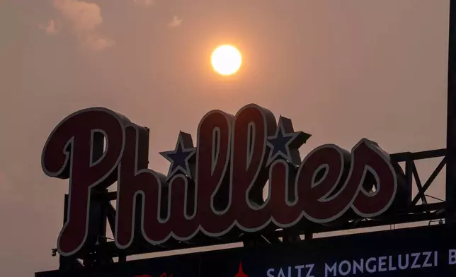 The Sun has an orange cast from smoke coming down from the Canadian wildfires as it sets near the Philadelphia Phillies scoreboard during the fourth inning of a baseball game against the New York Mets, Thursday, July 16, 2026, in Philadelphia. (AP Photo/Chris Szagola)
