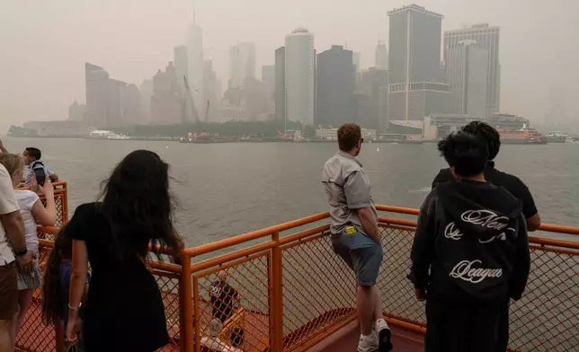 People take the Staten Island Ferry as smoke from wildfires blankets the sky, Thursday, July 16, 2026, in New York. (AP Photo/Yuki Iwamura)