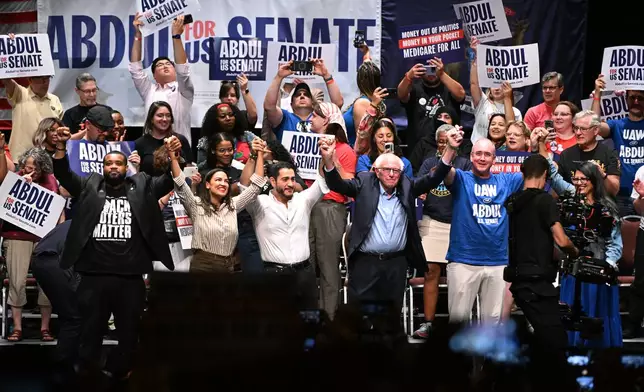From left foreground, Michigan state Rep. Donavan McKinney, D-Detroit, U.S. Rep. Alexandria Ocasio-Cortez, D-N.Y., Michigan Democratic U.S. Senate primary candidate Abdul El-Sayed, U.S. Sen. Bernie Sanders, I-VT., United Auto Workers President Shawn Fain, and U.S. Rep. Rashida Tlaib, D-Mich. join hands together following a campaign rally for El-Sayed, Saturday, July 18, 2026, in Detroit. (AP Photo/Jose Juarez)