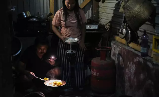 Tovi Murru, 32, and his wife Atoshi Ayemi serve food beside an empty liquefied petroleum gas cylinder inside their kitchen in Kohima, capital of the northeastern Indian state of Nagaland, Monday, July 6, 2026. (AP Photo/Yirmiyan Arthur)