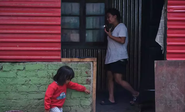 Atoshi Ayemi, 27, walks past her daughter Azatina, as she helps with cooking dinner in Kohima, capital of the northeastern Indian state of Nagaland, Monday, July 6, 2026. (AP Photo/Yirmiyan Arthur)