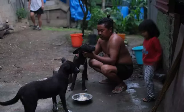 Tovi Murru, 32, pets his dog with his daughter Azatina, 3, by his side in Kohima, capital of the northeastern Indian state of Nagaland, Monday, July 6, 2026. (AP Photo/Yirmiyan Arthur)