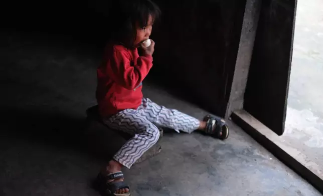 Azatina Murru, 3, eats an egg by the entrance of her home in Kohima, capital of the northeastern Indian state of Nagaland, Monday, July 6, 2026. (AP Photo/Yirmiyan Arthur)
