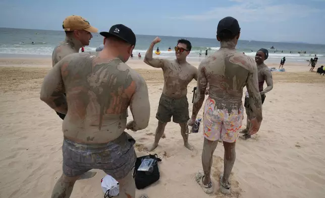 Visitors covered in a mud play during the Boryeong Mud Festival at a beach in Boryeong, South Korea, Saturday, July 25, 2026. (AP Photo/Lee Jin-man)