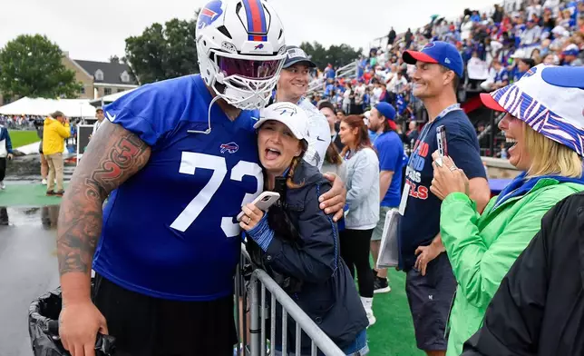 Buffalo Bills tackle Dion Dawkins (73) hugs Katie Rubert, of Rochester, N.Y., after practice at the team's NFL football training camp, Wednesday, July 29, 2026, in Pittsford, N.Y. (AP Photo/Adrian Kraus)