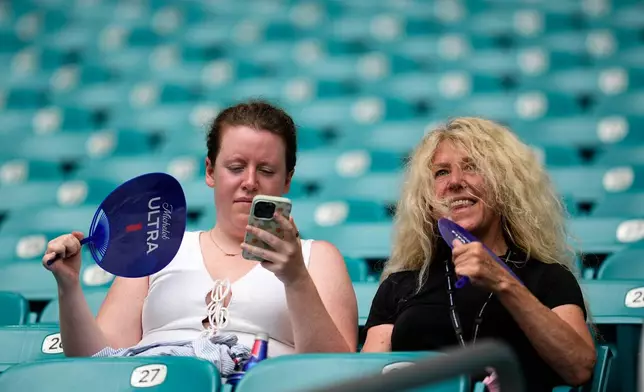 Spectators fan themselves before the World Cup quarterfinal soccer match between Norway and England in Miami Gardens, Fla., Saturday, July 11, 2026. (AP Photo/George Walker IV)