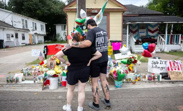 A couple spends a moment after placing flowers at the site where Lorenzo Salgado Araujo was shot by an ICE officer in Houston, Friday, July 10, 2026. (AP Photo/Annie Mulligan)