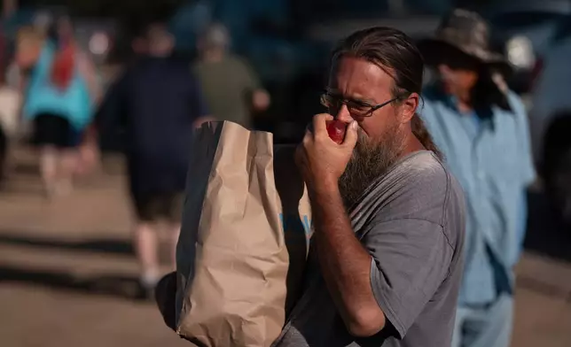 Matthew Cole smells a nectarine after receiving a bag of fruit during a free giveaway at Cesar Mora's orchard in Reedley, Calif., Wednesday, July 1, 2026. (AP Photo/Jae C. Hong)