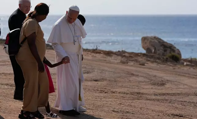 Pope Leo XIV walks together with a migrant family at the Gateway of Europe monument in Lampedusa, Sicily, southern Italy, Saturday, July 4, 2026, during a one-day pastoral visit to the island long associated with the plight of migrants crossing the Mediterranean. (AP Photo/Alessandra Tarantino)