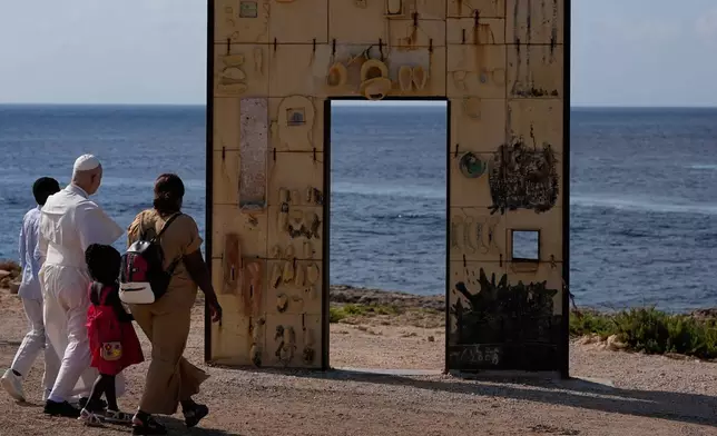 Pope Leo XIV walks together with a migrant family at the Gateway of Europe monument in Lampedusa, Sicily, southern Italy, Saturday, July 4, 2026, during a one-day pastoral visit to the island long associated with the plight of migrants crossing the Mediterranean. (AP Photo/Alessandra Tarantino)