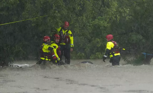 Members of the Boerne Fire Dept. maneuver through flood waters during a water rescue on Wednesday, July 15, 2026, in Boerne, Texas. (AP Photo/Darren Abate)