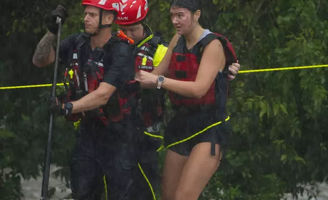Members of the Boerne Fire Dept. rescue a woman from flood waters on Wednesday, July 15, 2026, in Boerne, Texas. (AP Photo/Darren Abate)