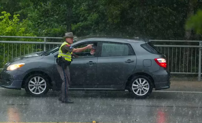 A Texas State Trooper speaks with a motorist who had attempted to drive through flood waters on Wednesday, July 15, 2026, in Boerne, Texas. (AP Photo/Darren Abate)