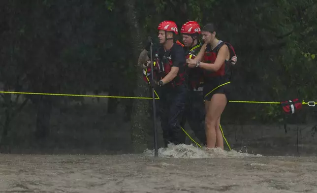 Members of the Boerne Fire Dept. rescue a woman from flood waters on Wednesday, July 15, 2026, in Boerne, Texas. (AP Photo/Darren Abate)