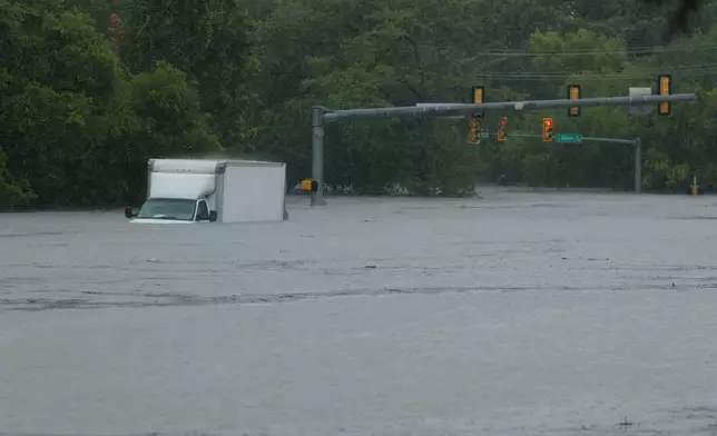 A truck sits submerged in flood waters at an intersection on Wednesday, July 15, 2026, in Boerne, Texas. (AP Photo/Darren Abate)