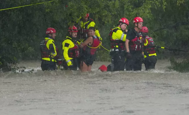 Members of the Boerne Fire Dept. rescue a woman from flood waters on Wednesday, July 15, 2026, in Boerne, Texas. (AP Photo/Darren Abate)