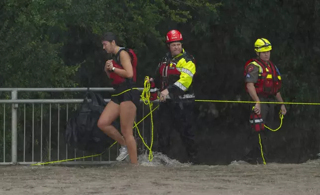Members of the Boerne Fire Dept. rescue a woman from flood waters on Wednesday, July 15, 2026, in Boerne, Texas. (AP Photo/Darren Abate)