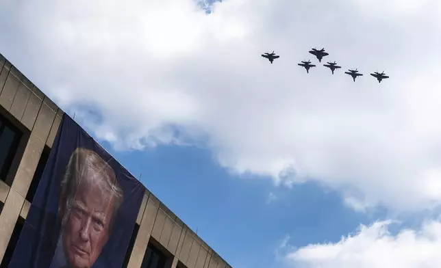 A flight of F-18s, F-35s and a F-22 fly past a picture of President Donald Trump hanging on the U.S. Department of Labor near the Great American State Fair on the National Mall, Friday, July 3, 2026, in Washington. (AP Photo/Nathan Howard)