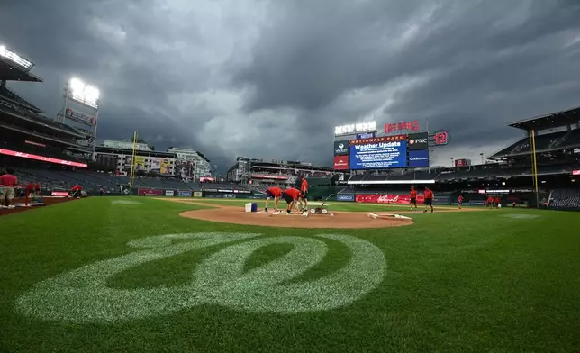 The Washington Nationals grounds crew works on the field as the baseball game between the Washington Nationals and the Toronto Blue Jays is being delayed due to inclement weather in the area, Tuesday, July 28, 2026, in Washington. (AP Photo/Nick Wass)