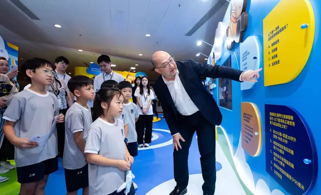 Raymond Tam, Executive Director, Corporate Affairs of The Hong Kong Jockey Club, visits the Club’s exhibition at the Hong Kong Book Fair and interacts with primary school students.