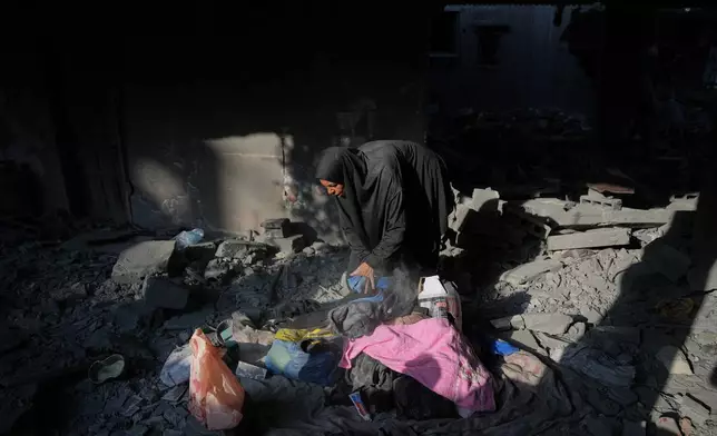 A Palestinian woman saves belongings from a destroyed building following an Israeli airstrike last night, at al-Bureij refugee camp, central Gaza Strip, Thursday, July 16, 2026. (AP Photo/Abdel Kareem Hana)